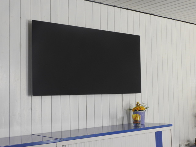 Schwarzes Infrarot-Paneel an einer weiß verkleideten Holzwand über einem Sideboard.